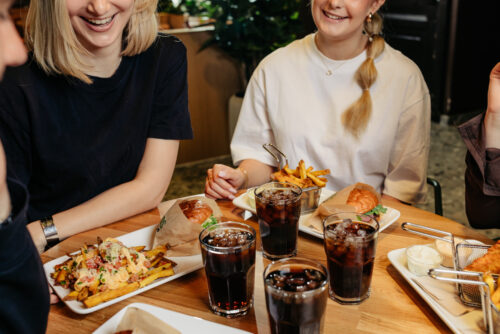 Nuoret syömässä burgeriaterioita ravintolan pöydässä.